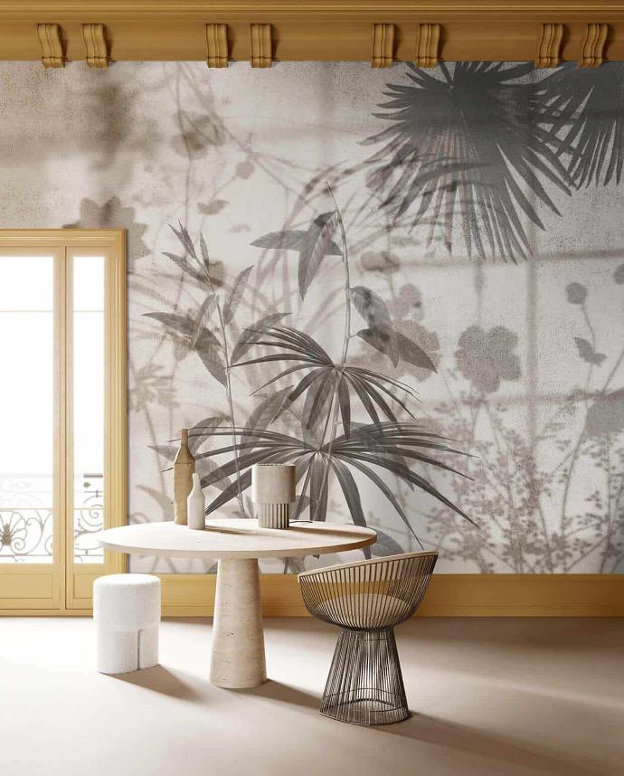 Une élégante table à manger au design minimaliste, située dans un espace à double hauteur, est ornée d'un superbe papier peint panoramique. Ce dernier met en scène des silhouettes végétales se dessinant sur un fond en béton gris.